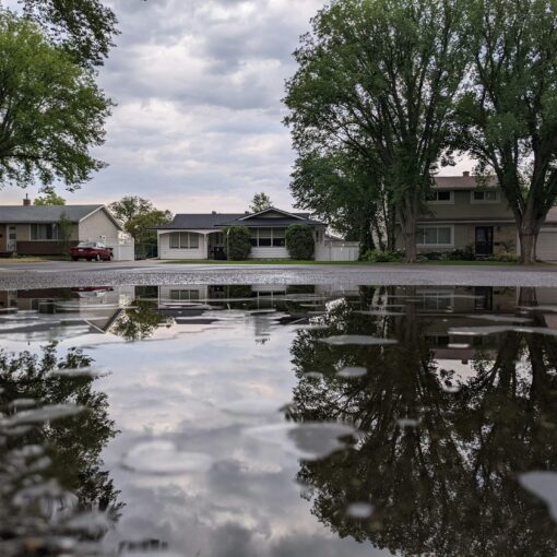 A single family home shown in the reflection of water in a street