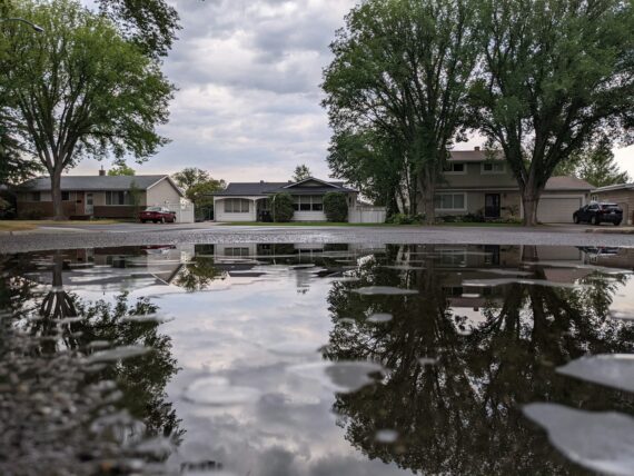 A single family home shown in the reflection of water in a street